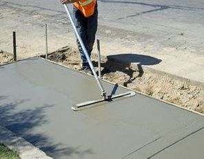 Workman finishes and smooths concrete surface on new sidewalk